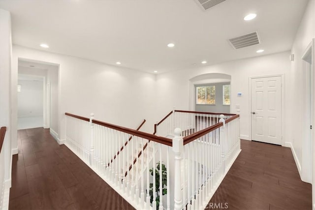 hallway with recessed lighting, visible vents, dark wood finished floors, and an upstairs landing