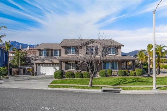 view of front of house with stucco siding, a mountain view, a garage, driveway, and a front lawn