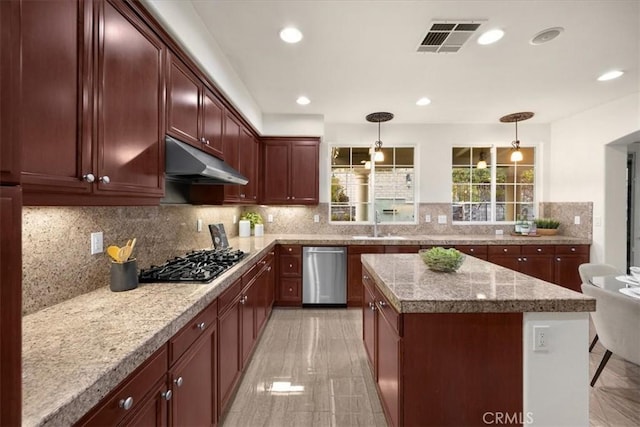 kitchen with visible vents, hanging light fixtures, stainless steel appliances, light countertops, and under cabinet range hood