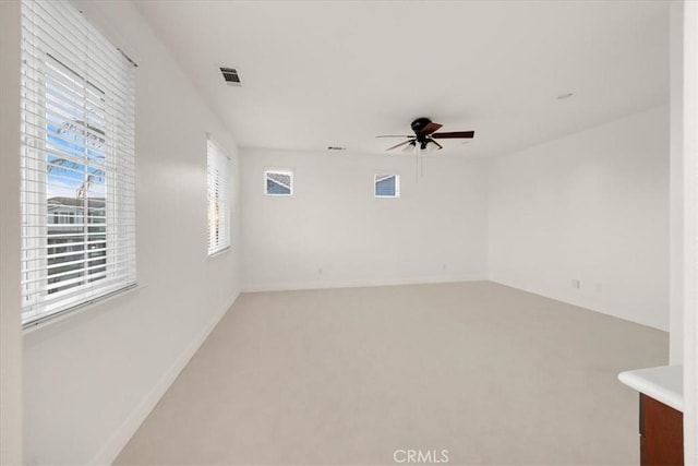 carpeted spare room featuring baseboards, visible vents, and a ceiling fan