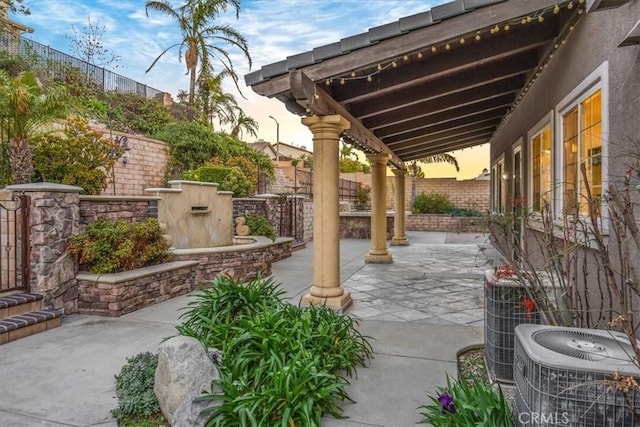 patio terrace at dusk featuring a fenced backyard and central AC