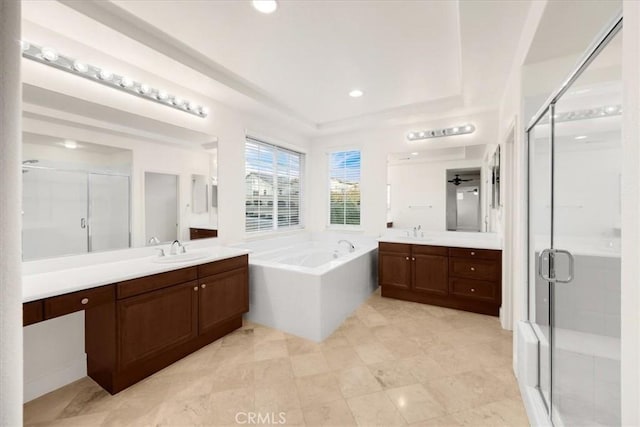 bathroom with a garden tub, a shower stall, two vanities, and a sink