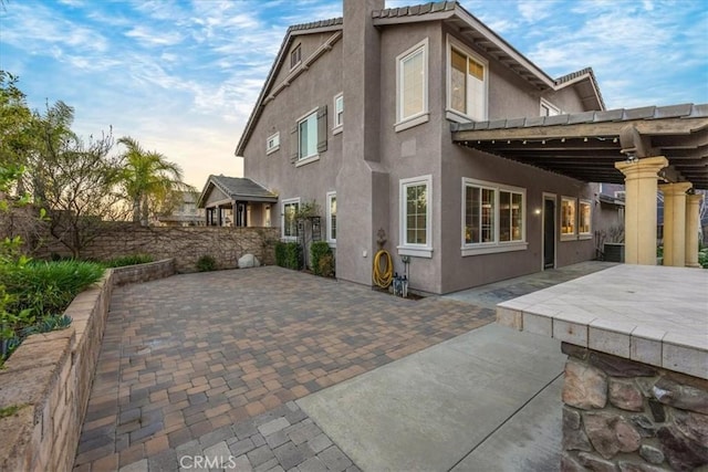 back of property with a tiled roof, a patio area, and stucco siding