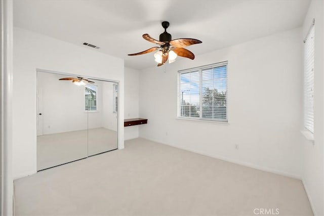 unfurnished bedroom with light carpet, ceiling fan, a closet, and visible vents