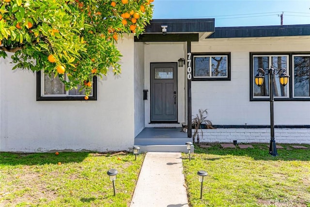 property entrance with a lawn and stucco siding