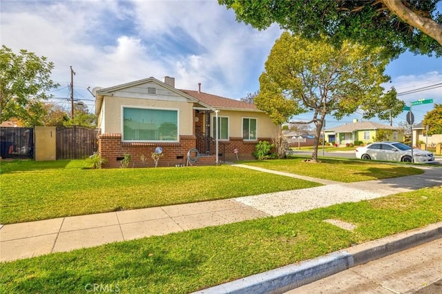 view of front of property with brick siding, a chimney, stucco siding, a front yard, and fence