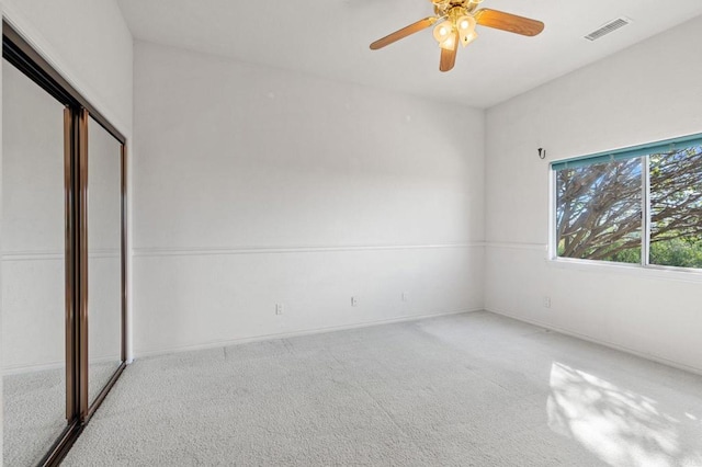 unfurnished bedroom featuring a ceiling fan, a closet, visible vents, and light colored carpet