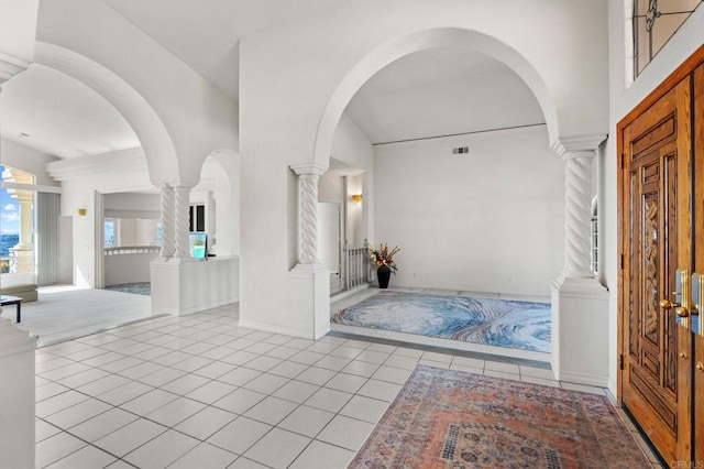 entrance foyer with light tile patterned floors, a high ceiling, visible vents, and ornate columns