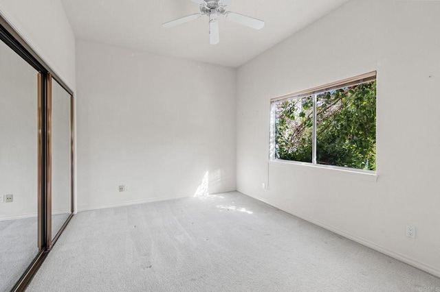 empty room with light carpet, ceiling fan, and baseboards