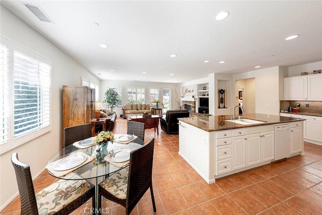 kitchen featuring visible vents, dark countertops, open floor plan, white cabinetry, and a sink