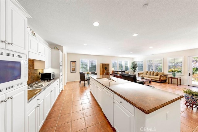 kitchen with a spacious island, white appliances, and white cabinetry