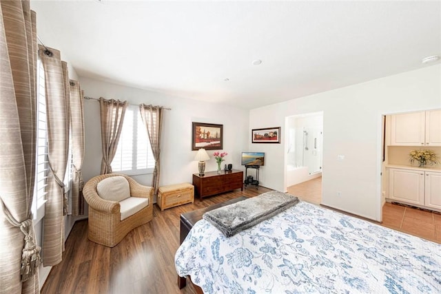 bedroom with light wood-style floors and connected bathroom