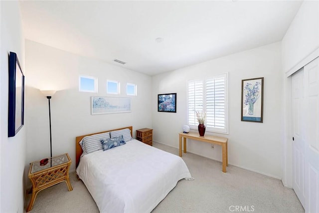 bedroom with a closet, visible vents, and light colored carpet