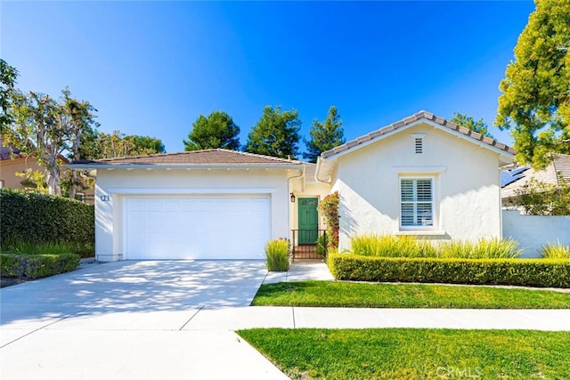 view of front facade featuring driveway, an attached garage, a tiled roof, and stucco siding