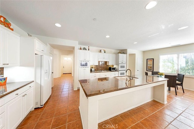 kitchen with tasteful backsplash, a center island with sink, stainless steel appliances, white cabinetry, and recessed lighting