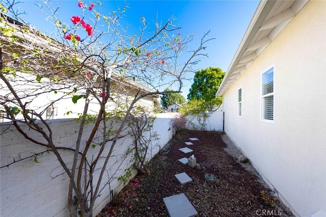 view of side of home featuring a fenced backyard and stucco siding