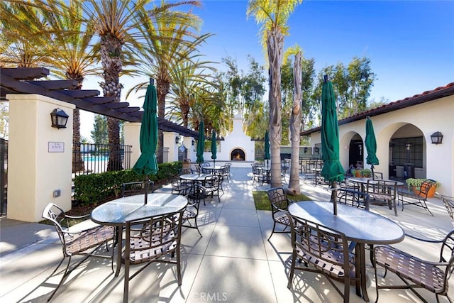 view of patio with outdoor dining space, fence, and a pergola