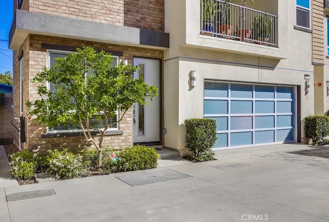 entrance to property with concrete driveway, an attached garage, and stucco siding