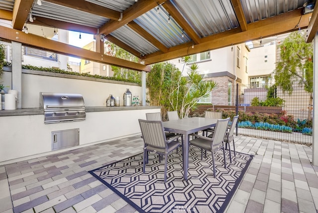 view of patio / terrace with outdoor dining area, an outdoor kitchen, a grill, and fence