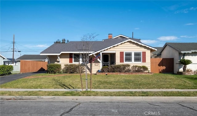 view of front of property featuring driveway, a front lawn, and fence