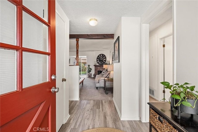 foyer with a textured ceiling, light wood finished floors, a fireplace, and visible vents