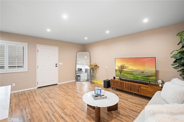 living area featuring baseboards, light wood finished floors, and recessed lighting