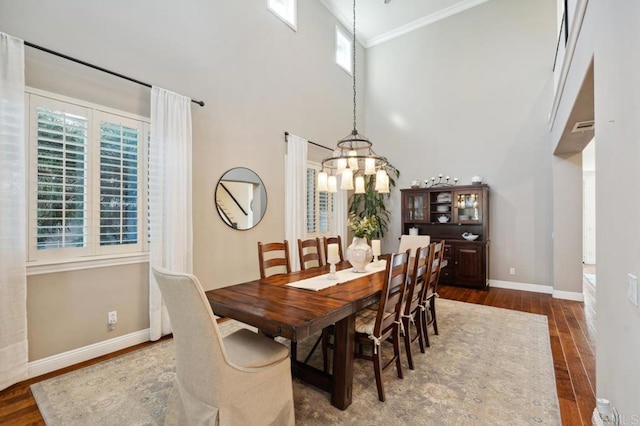 dining space with a high ceiling, wood finished floors, and baseboards