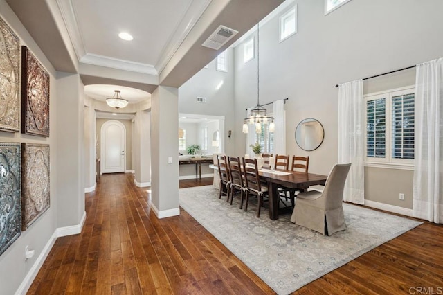 dining room with arched walkways, dark wood-style flooring, visible vents, ornamental molding, and baseboards