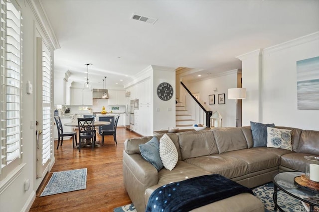 living room featuring stairway, visible vents, dark wood finished floors, and ornamental molding