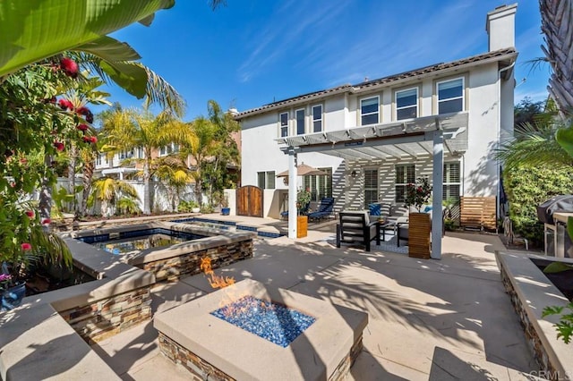 rear view of property with a patio, a fire pit, an in ground hot tub, a pergola, and a chimney