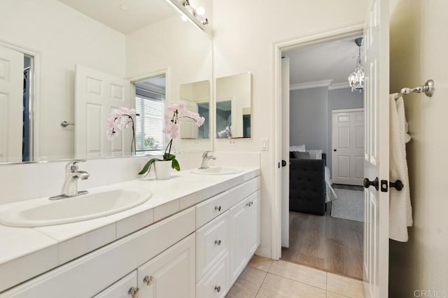 ensuite bathroom with double vanity, ornamental molding, a sink, and tile patterned floors