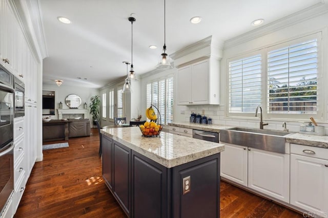 kitchen with crown molding, white cabinetry, a sink, and a center island