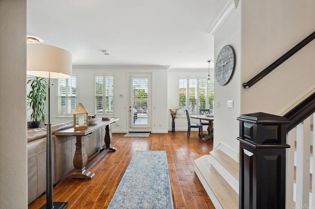 foyer entrance with hardwood / wood-style flooring, visible vents, a healthy amount of sunlight, ornamental molding, and stairway