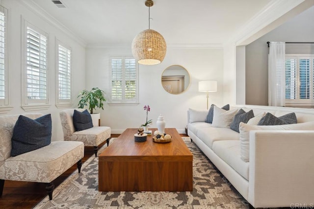 living room with baseboards, wood finished floors, visible vents, and crown molding