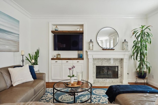 living room with ornamental molding, a fireplace, baseboards, and wood finished floors