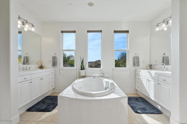 full bathroom featuring two vanities, a sink, and a garden tub