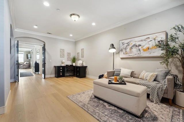 living room featuring light wood finished floors, baseboards, arched walkways, and crown molding