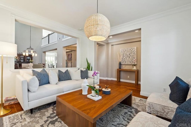 living area featuring crown molding, baseboards, wood finished floors, and a notable chandelier