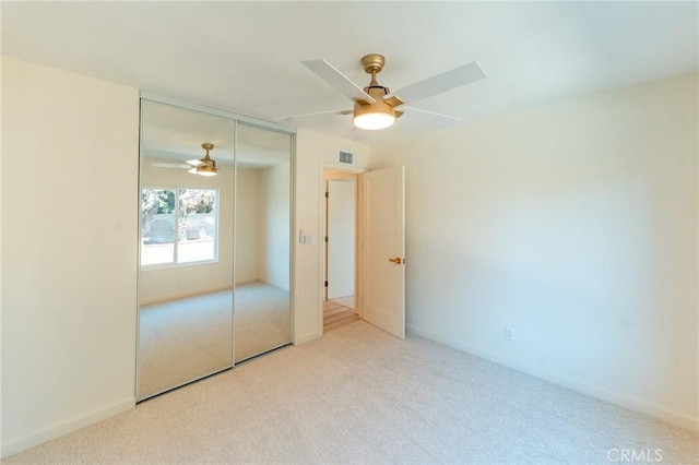 unfurnished bedroom featuring ceiling fan, visible vents, a closet, and light colored carpet