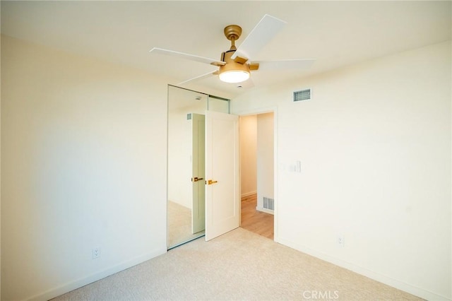 empty room featuring light carpet, visible vents, and a ceiling fan