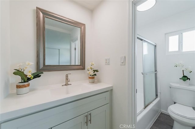 full bathroom with enclosed tub / shower combo, vanity, and toilet