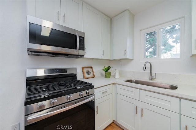 kitchen featuring light countertops, appliances with stainless steel finishes, a sink, and white cabinetry