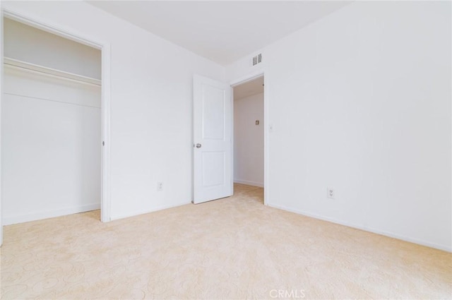 unfurnished bedroom featuring a closet, visible vents, and light carpet