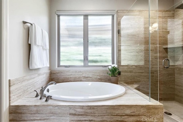 full bathroom with a shower stall and a bath