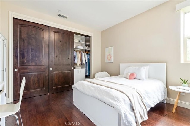 bedroom featuring dark wood-style floors, a closet, visible vents, and baseboards