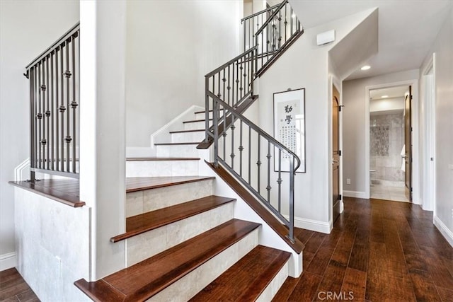 stairway with baseboards, wood finished floors, and recessed lighting