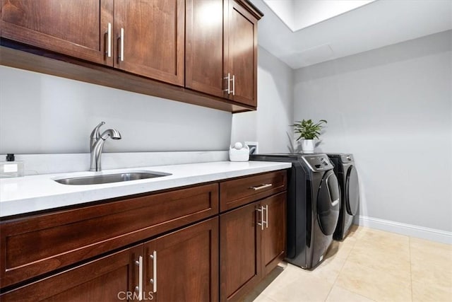 laundry room featuring cabinet space, light tile patterned floors, baseboards, washer and clothes dryer, and a sink