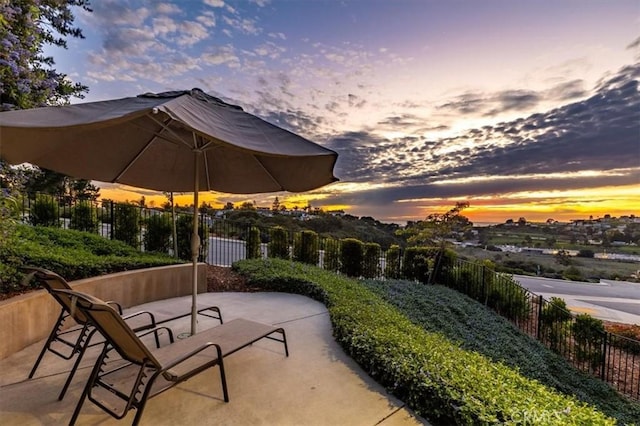 patio terrace at dusk featuring fence