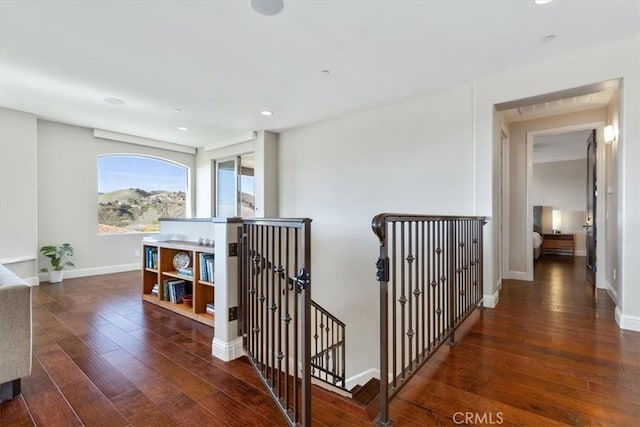 corridor with recessed lighting, dark wood finished floors, an upstairs landing, and baseboards