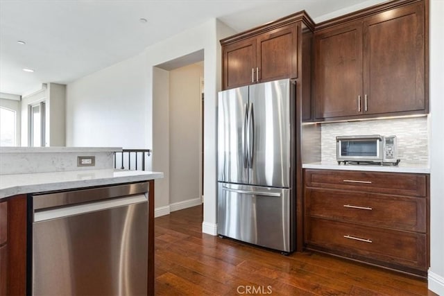 kitchen featuring dark wood-style flooring, a toaster, stainless steel appliances, tasteful backsplash, and baseboards